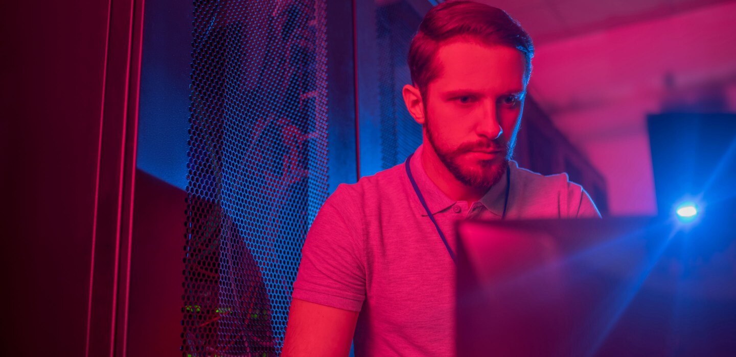 A man in a room with a red light looking at a monitor