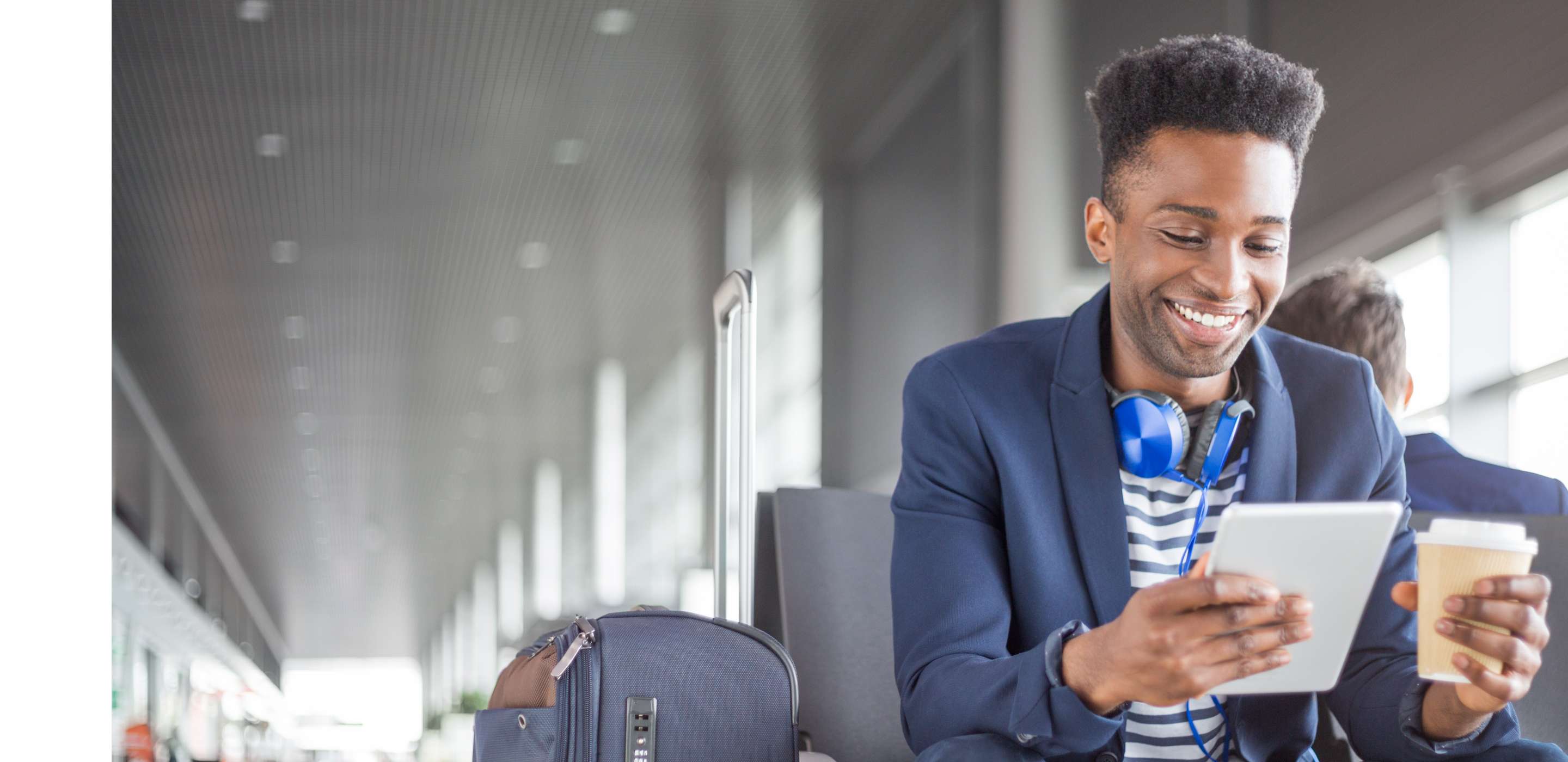 A man holding a cup and tablet sitting down