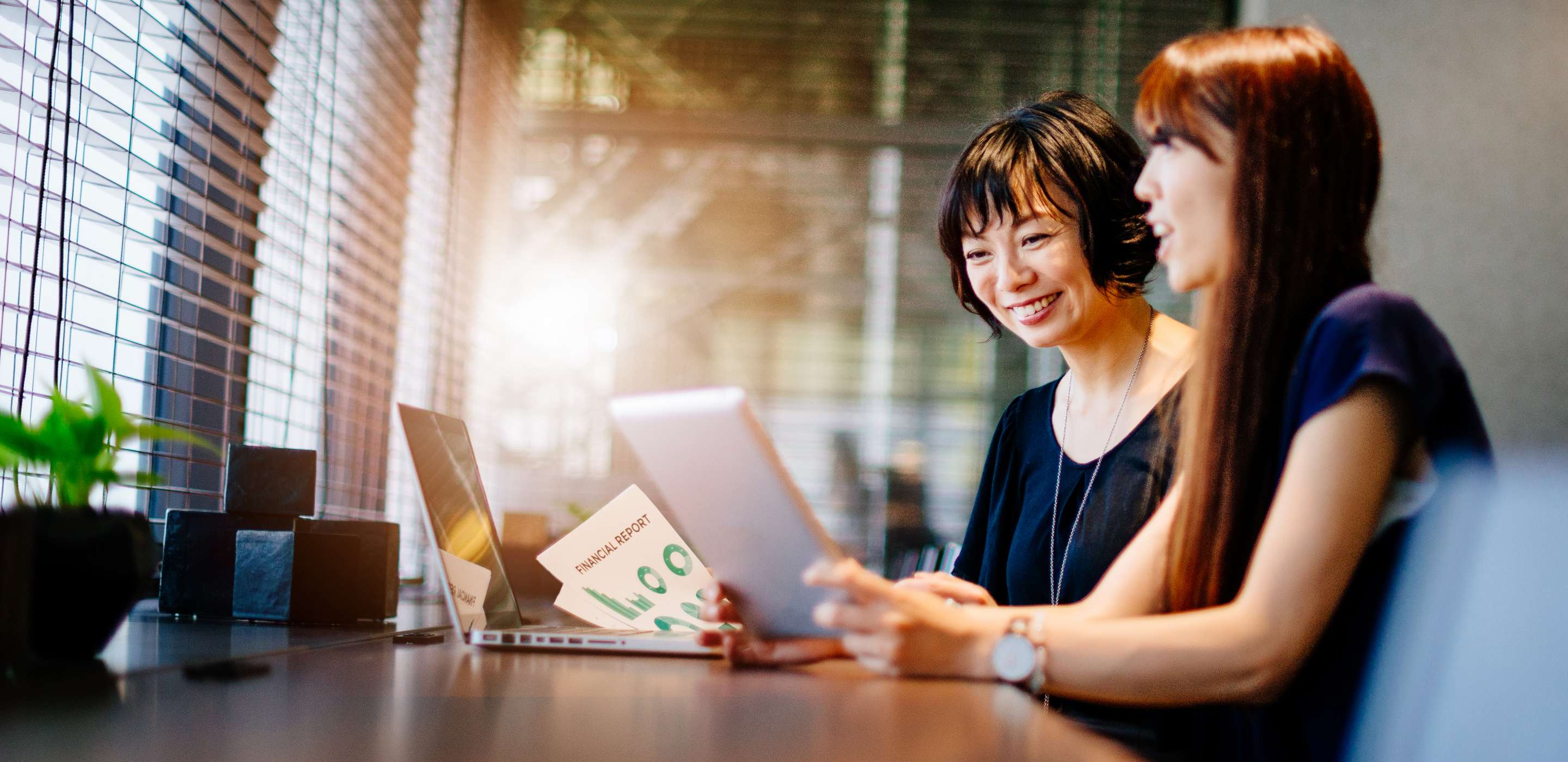 2 Ladies working on a laptop, smiling