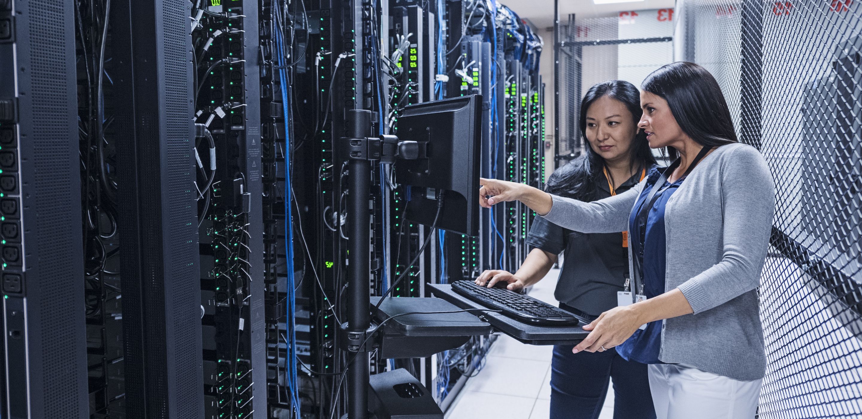 Two woman looking at a screen in a server room