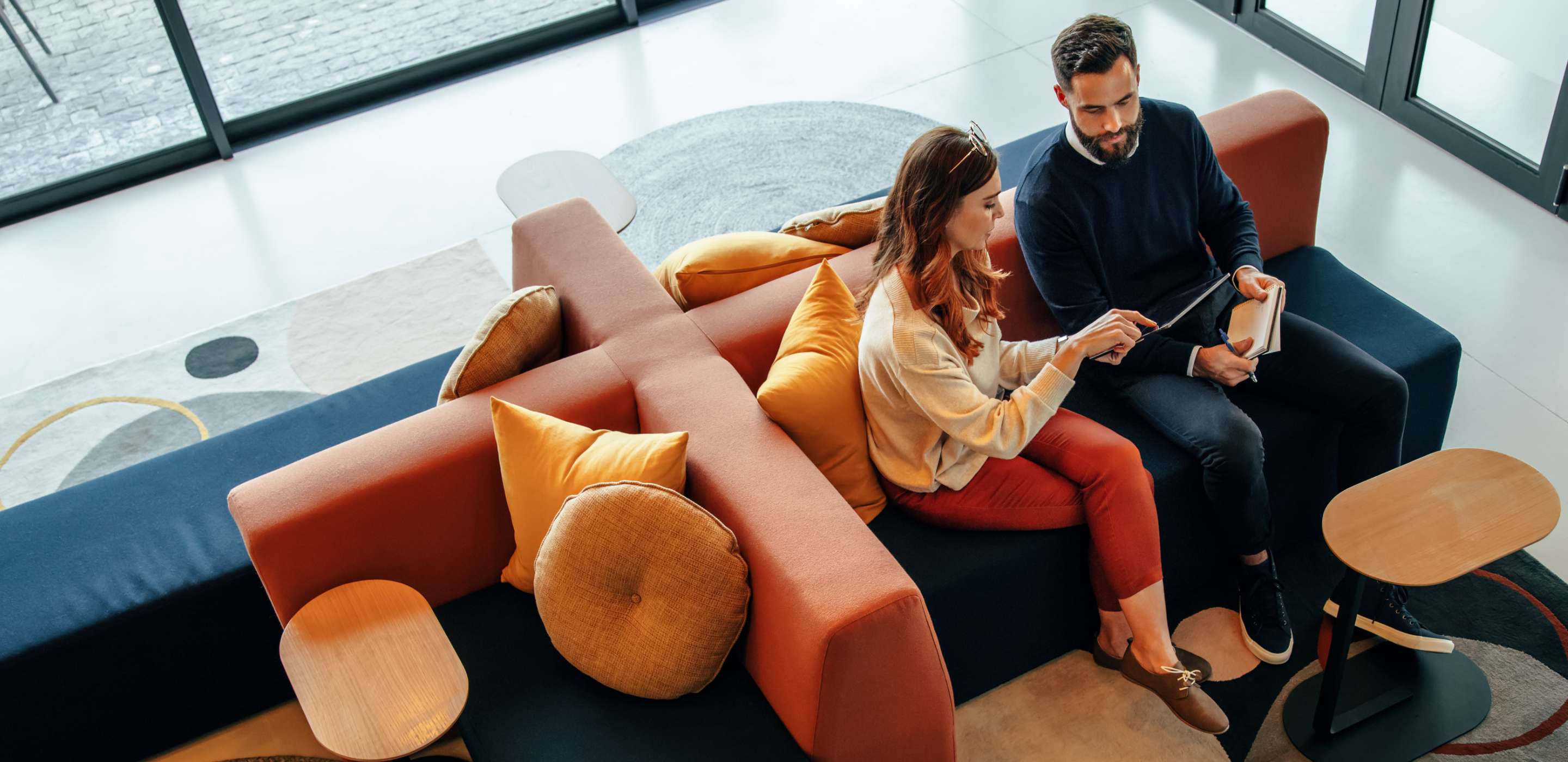 High angle view of two businesspeople working in an office lobby using a digital tablet while having a discussion