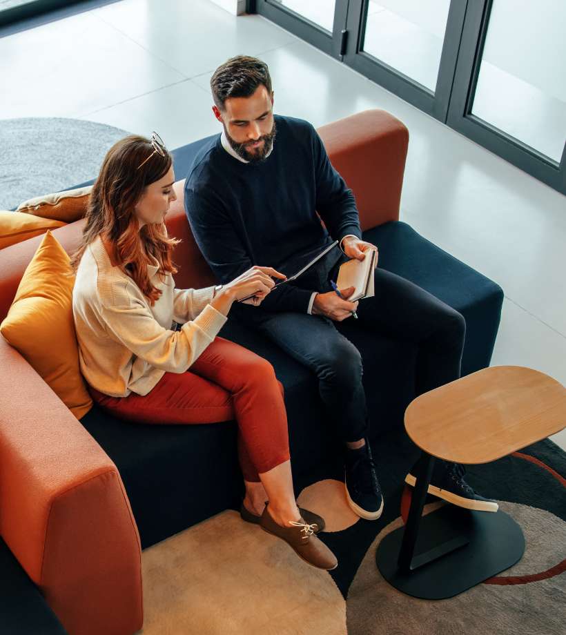High angle view of two businesspeople working in an office lobby using a digital tablet while having a discussion