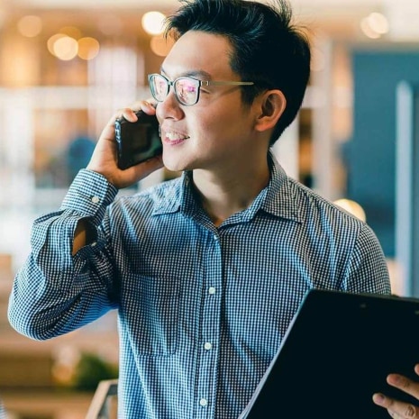 Man carrying his tablet while talking on a mobile phone