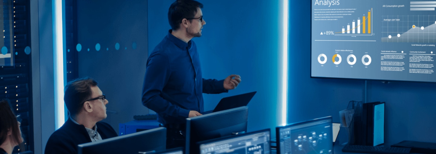 Two men in a room and looking at a dashboard on a large screen
