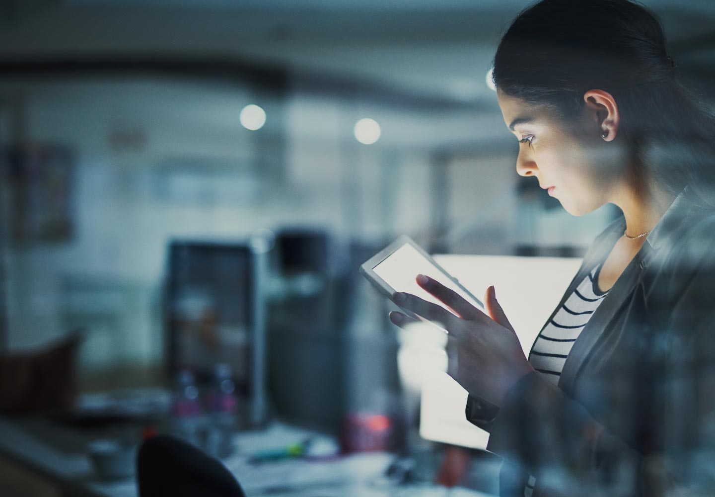Woman in office at night working on a tablet