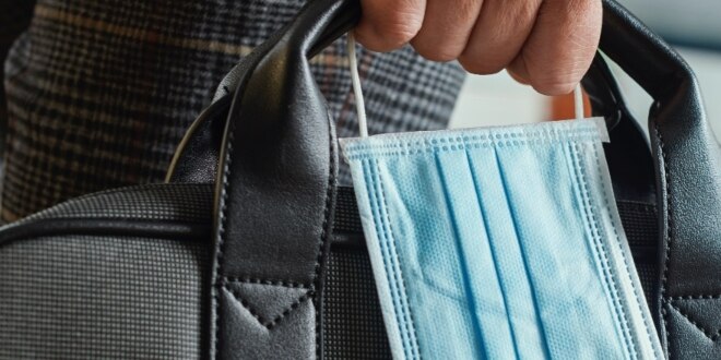 Man holding a briefcase and a face mask