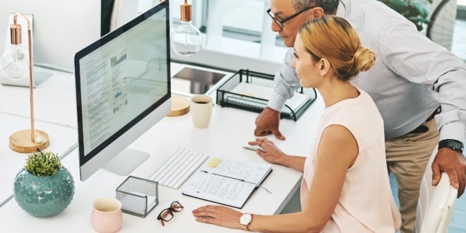 A guy and a lady looking over a big computer screen